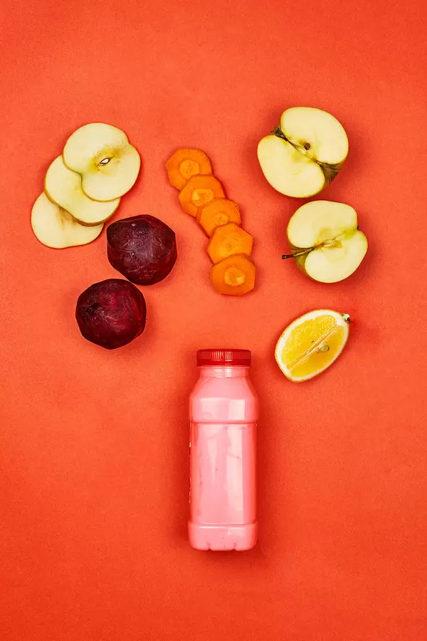 Detox juice with organic fruits and vegetables cuts on red background