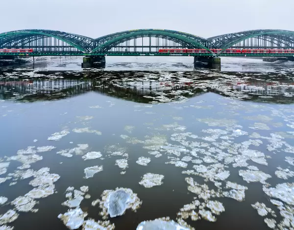 Deutsche Bahn trains crossing Hamburg bridge in the winter with ice floes flowing beneath in Elbe river