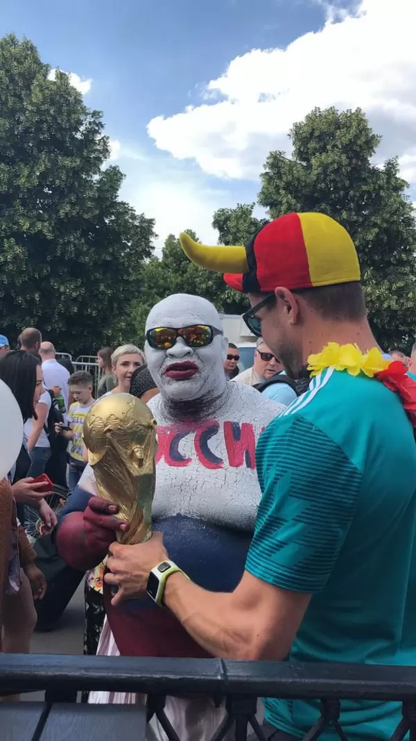 Deutscher und russischer Fußball-Fan halten zusammen den WM-Pokal