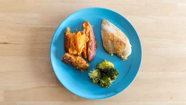 Diät Mahlzeit - Hühnerbrust mit Broccoli und Süßkartoffeln auf einem blauen Teller