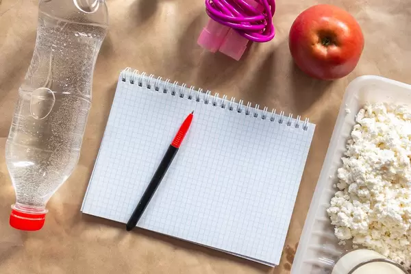 Diät planen mit der Erstellung eines Essensplan, Springseil, Wasserflasche und Apfel als gesundes Lebensmittel