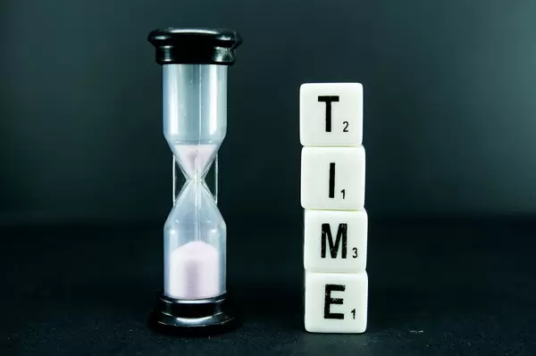 Dice reading TIME with a sand clock beside