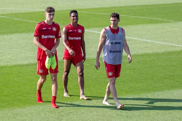 Die drei Fußballer Lucas Alario, Wendell und Kai Havertz gehen nach dem Fußballtraining glücklich und barfuß vom Spielfeld
