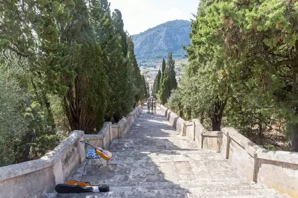 Die Freitreppe Carrer del Calvari in Pollença mit Skulpturen und der Gitarre eines Straßenmusikers
