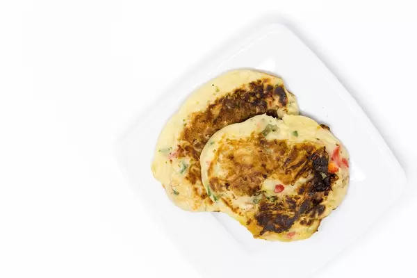 Die Herzhaften Bananenpfannkuchen des Hello Fresh - Karibischer Süßkartoffel-Kokos-Eintopf mit Bohnen Rezeptes auf weißem Teller mit weißem Hintergrund - Aufsicht