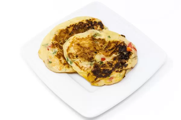 Die Herzhaften Bananenpfannkuchen des Hello Fresh - Karibischer Süßkartoffel-Kokos-Eintopf mit Bohnen Rezeptes auf weißem Teller mit weißem Hintergrund