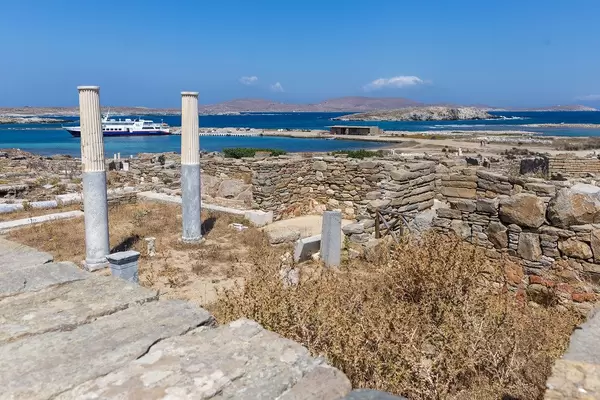 Die Ruinen von Delos Theater-Viertel mit blauem Meer und Fähre im Hintergrund