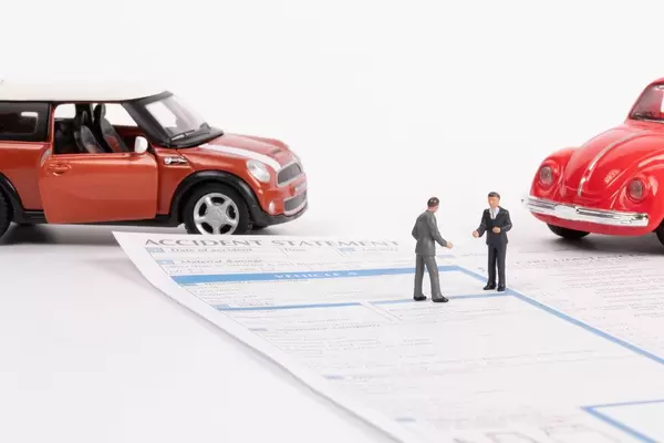 Die Szene nach einem Unfall mit zwei Autos, zwei Menschen und ein Schadensbericht
