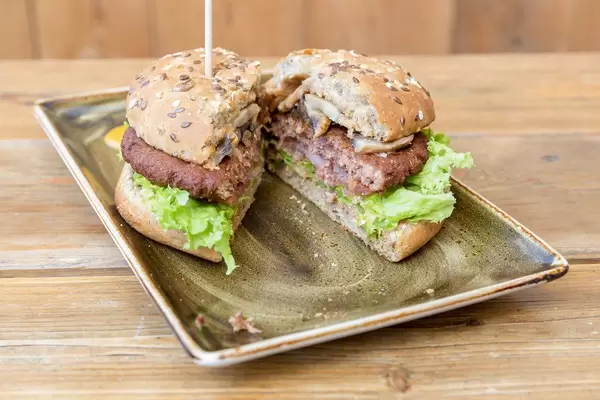 Die vegan Fleischalternative, Naturbursche-Burger bei "Hans im Glück", durchgeschnitten, mit Blattsalat, Pilzen, Getreide und Erbsenproteinen