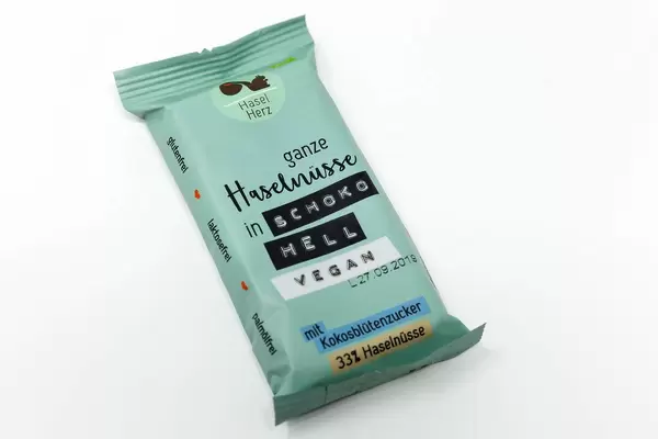 Die vegane Schokolade von HaselHerz mit Kokosblütenzucker und ganzen Haselnüssen in Schoko Hell ist laktosefrei, glutenfrei und palmölfrei