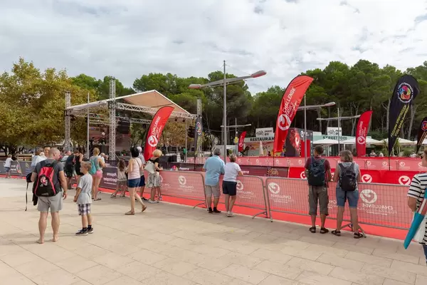Die Ziellinie eines Triathlons, Menschen warten an Zäunen auf die Ankunft der ersten Läufer