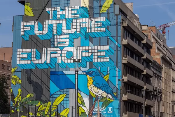 'Die Zukunft liegt in Europa' Streetart Stück in Brüssel geschrieben auf einem blauen und gelben Hintergrund mit Vögeln auf einer 30 Meter hohen Hauswand