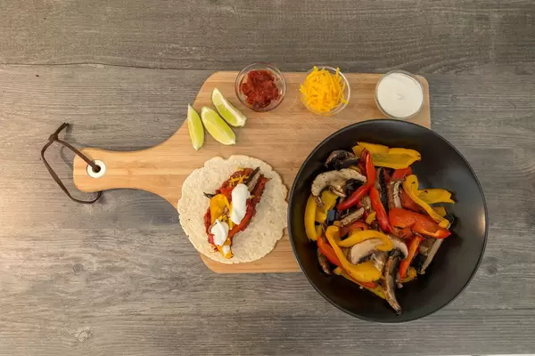Die Zutaten für das Hello Fresh Rezept: Die Zutaten für das Hello Fresh Rezept: Vegetarische Fajitas mit Paprika & Pilzen selbst gemachter, scharfer Soße und Limettenschmand in der Aufsicht auf einem Brettchen
