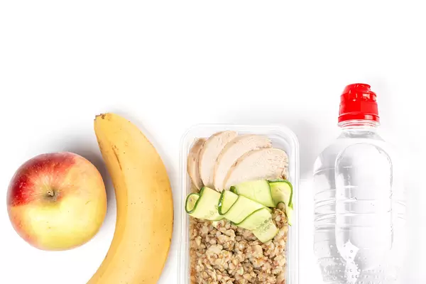 Diet food on a white background, fresh vegetables and fruits, buckwheat, chicken and water in bottle