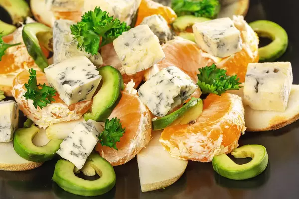 Diet salad with pear, avocado, tangerines and dorblu, close-up
