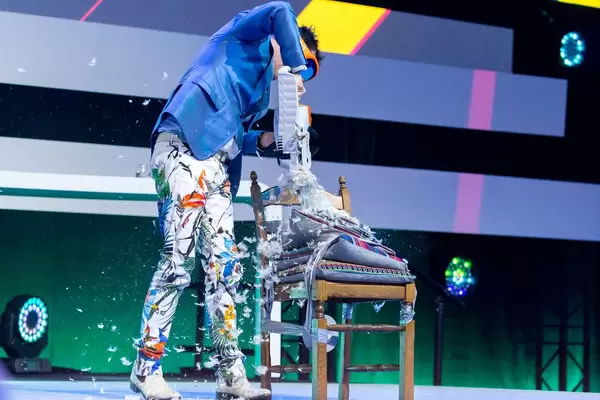 Dietmar Dahmen sägt in ein Stuhl mit Kissen als Teil seiner Bühnenshow auf der Digital X in Köln