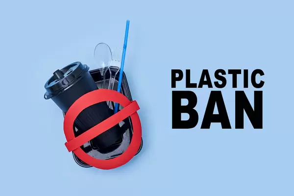 Different plastic items and red restriction sign with text - Plastic ban