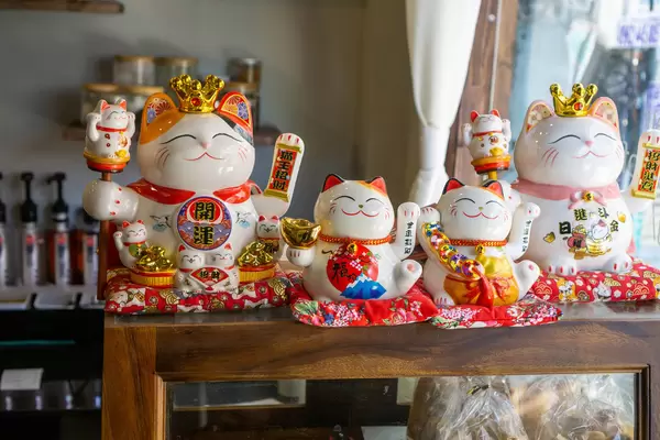 Different sized Maneki-neko Lucky Cats with Golden and Red Decorations to bring Luck in a Cafe in Ho Chi Minh City, Vietnam