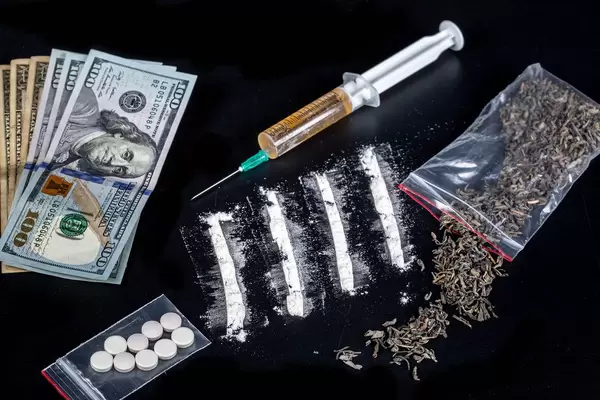 Different types of drugs and dollars on a black background