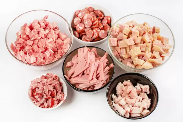 Different types of meat and sausages sliced in bowls