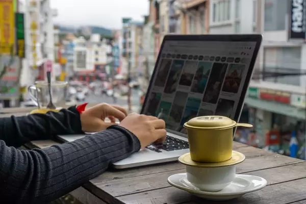 Digital Nomad working on a Laptop while drinking Vietnamese Coffee and enjoying a City View