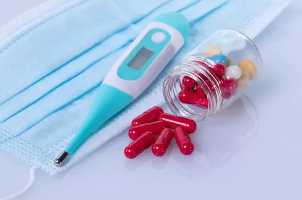 Digital thermometer with medical face mask and red pills