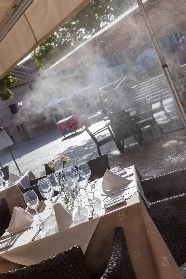 Dinner für vier Personen: gedeckter Tisch im Restaurant mit vier Gedecken und Blick auf den Platz