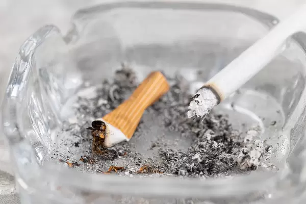 Dirty ashtray and smoked cigarettes with health danger concept