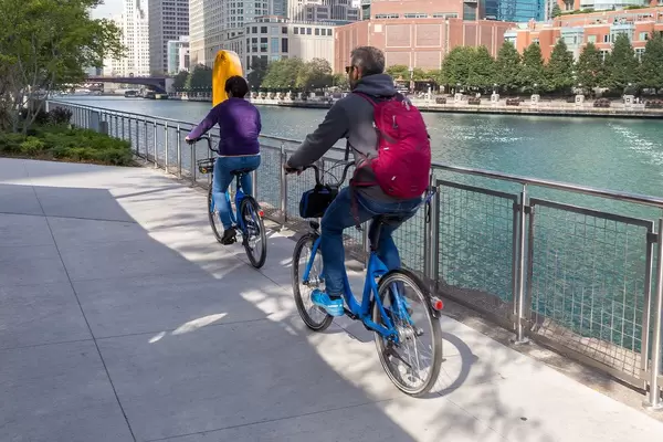 Discovering Chicago by bike: man and woman cycle along the Chicago River on a sunny day using the bike sharing program Divvy