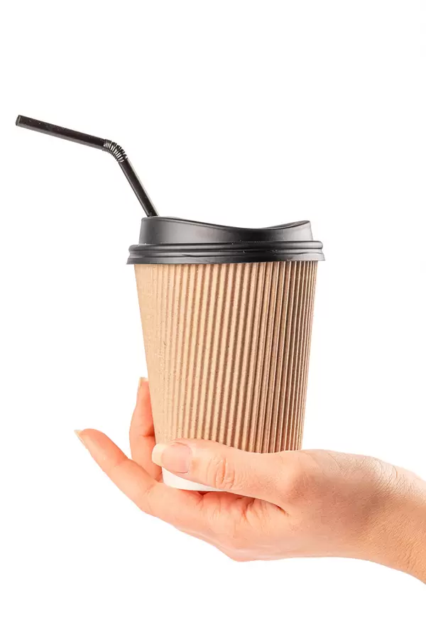 Disposable coffee cup with a lid and a straw in a woman's hand