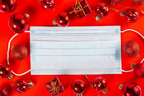 Disposable medical mask on red background with red balls and gifts