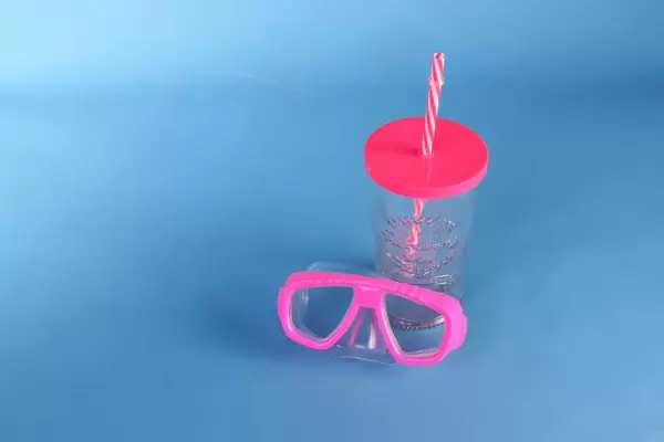 Diving mask and drinking glass on blue background