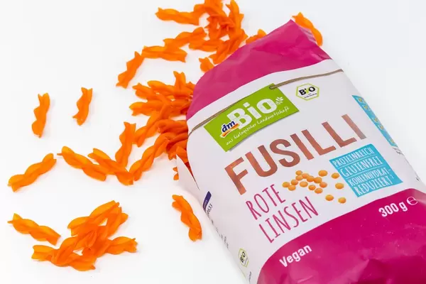 DM Bio Fusilli aus roten Linsen aus der Verpackung verschüttet auf weißem Hintergrund