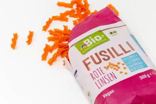 DM Bio Fusilli made from red lentils spilled on white background