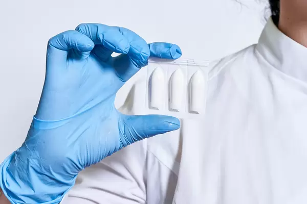 Doctor hand holds hemorrhoidal suppository