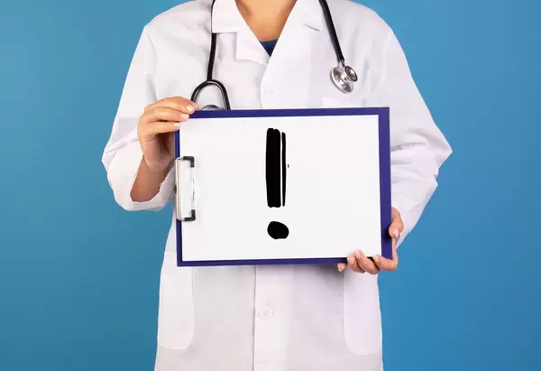 Doctor holding clipboard with exclamation point