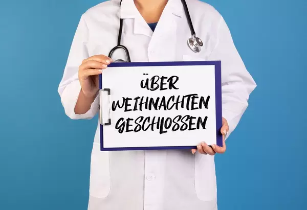 Doctor holding clipboard with über Weihnachten geschlossen text