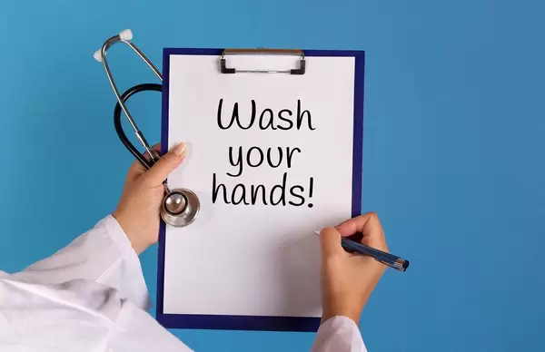 Doctor holding clipboard with Wash your hands text