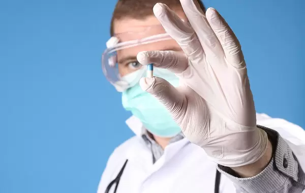 Doctor holding small pill