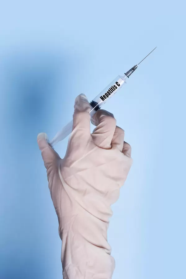 Doctor in medical gloves holds a syringe with Hepatitis C text on it