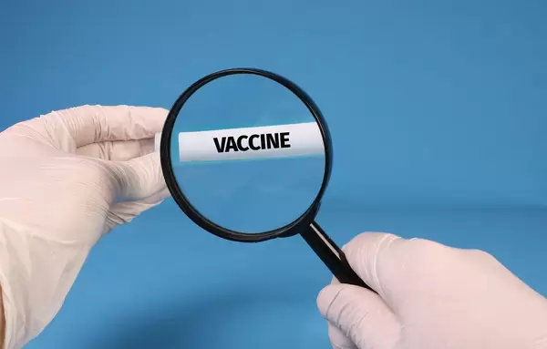 Doctor in surgical gloves with magnifying glass looking and zooming on Vaccine