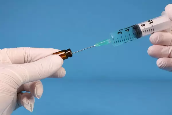 Doctor or nurse filling a syringe on blue background