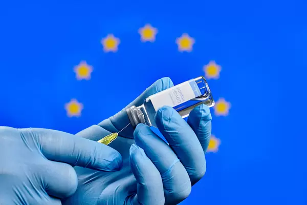 Doctor preparing Covid-19 injection against the European Union flag