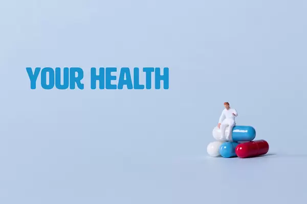 Doctor sitting on a stack of pills with Your Health text