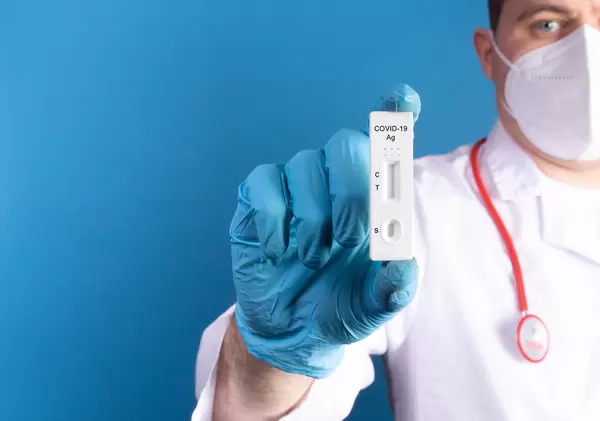 Doctor wearing latex gloves holds a covid-19 antigen test