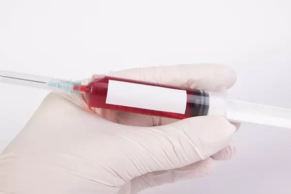 Doctor's hand wearing latex rubber disposable gloves and holding injection needle