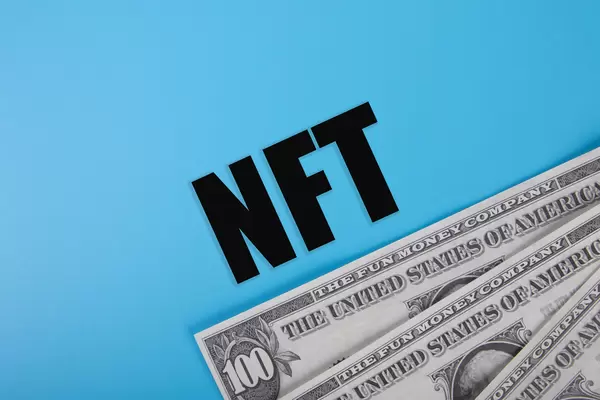 Dollar banknotes and NFT text on blue background