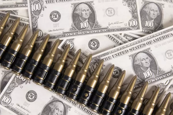 Dollar banknotes with rifle bullets