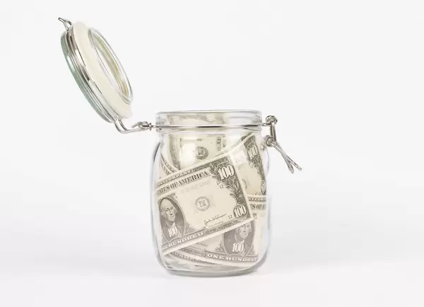Dollar bills in glass jar on white background