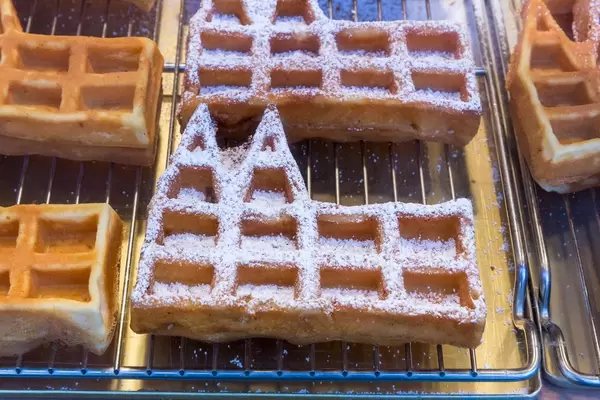 Dom waffles, waffles in the shape of the Cologne Cathedral, some with powdered sugar, on baking grid